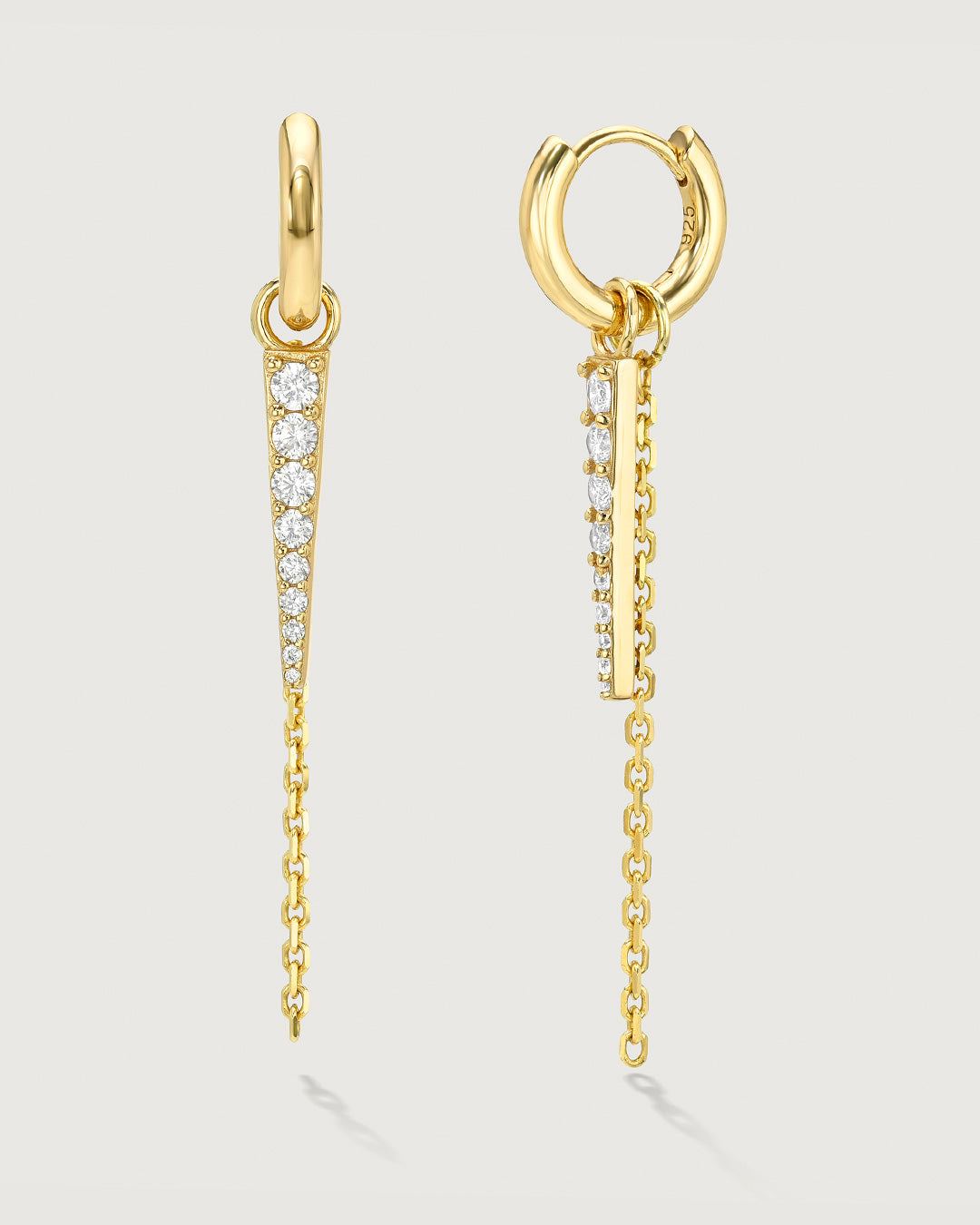 Product photo of gold huggy earrings with a chain and gemstone charm by Camóre