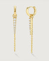 Product photo of gold huggy earrings with a chain and gemstone charm by Camóre