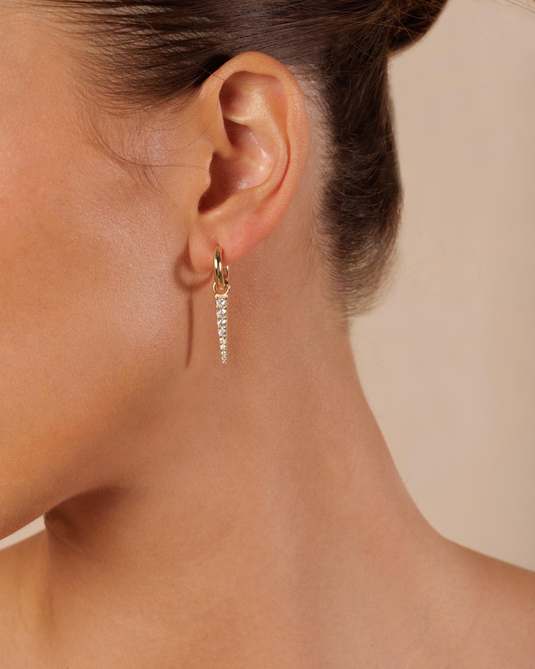 photo of a model wearing gold huggy earrings with a gemstone charm by Camóre